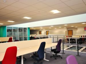 Open plan office space showing desks, chairs, and the light well.