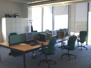 Open plan office with desks, chairs, computers and storage space