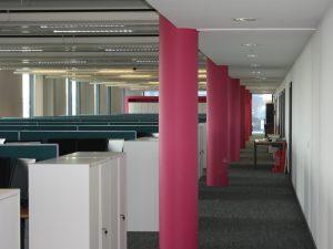 Open plan office space with pink columns along the walkway