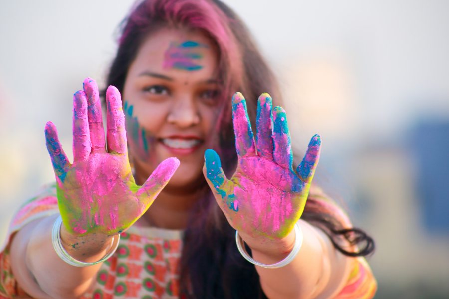 Creative banner - someone holding up their hands which are covered in brightly coloured paint, she looks really happy