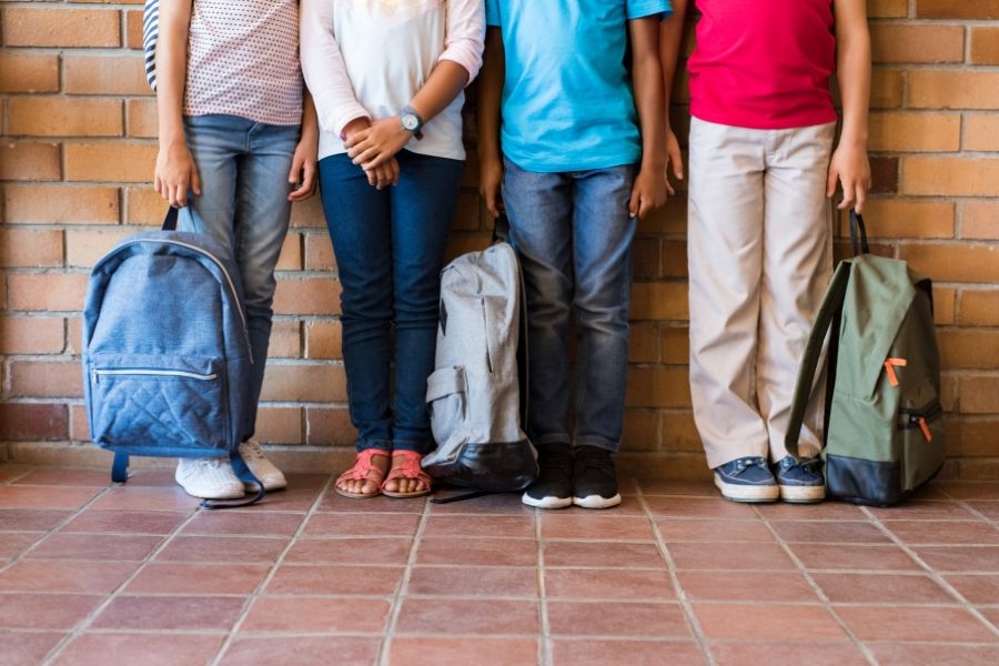 A line of people visible from the waist down, holding rucksacks