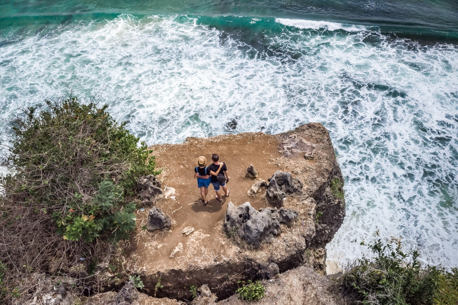 Two people stood on a cliff overlooking the sea