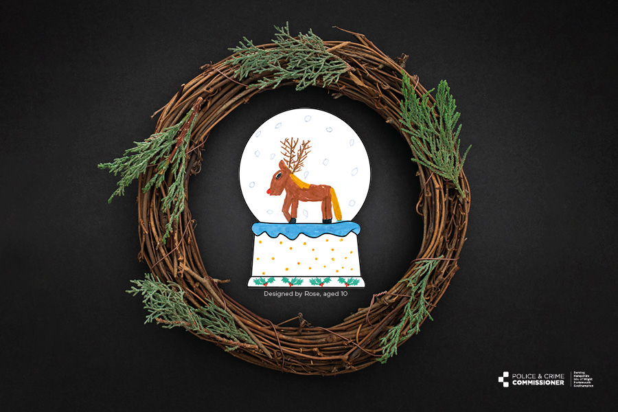 black background, child drawing of a snow globe with a reindeer in it, surrounded by a wreath. The globe was designed by Rose, aged 10.