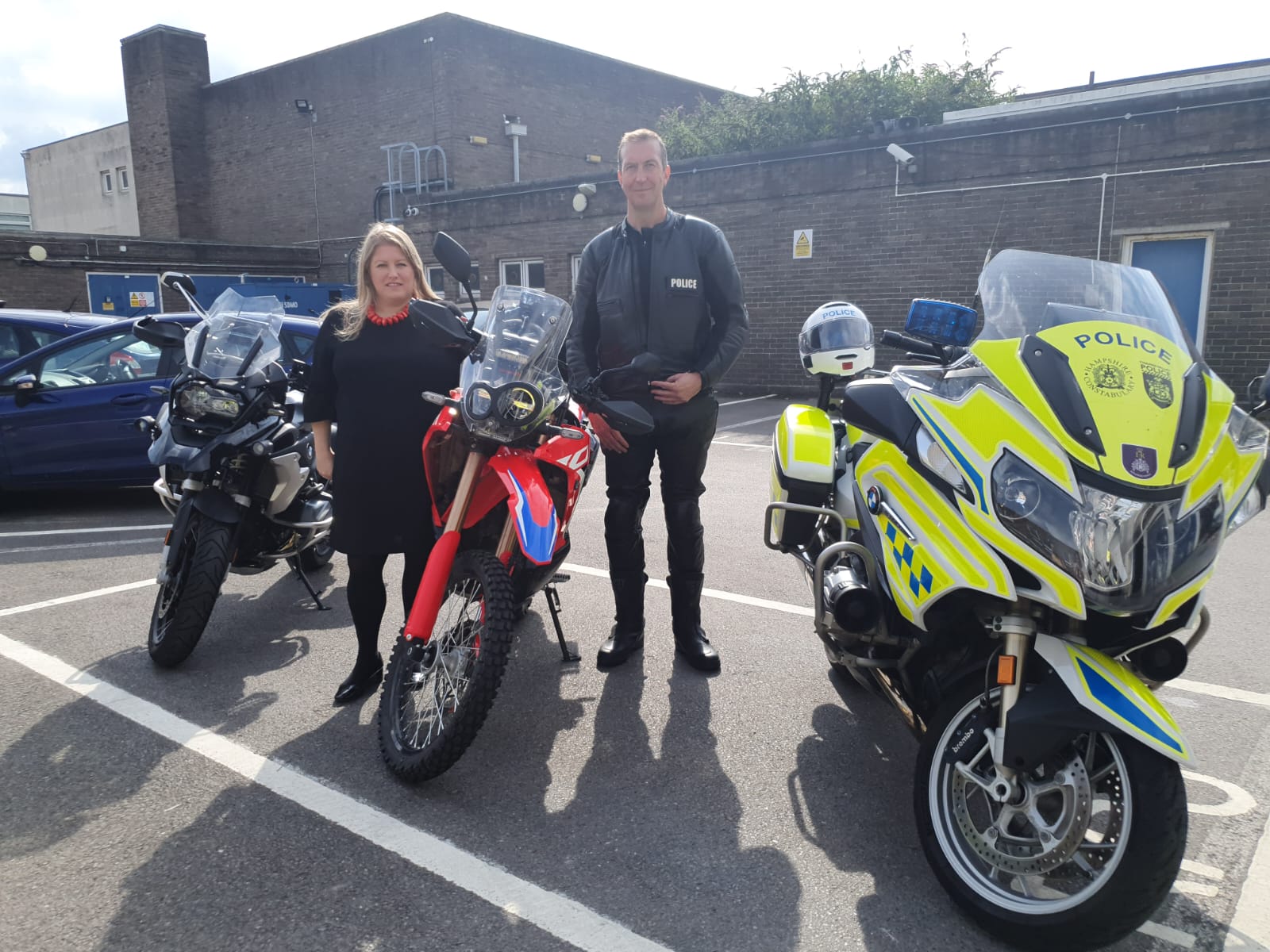 Donna standing with an officer behind two police bikes, smiling