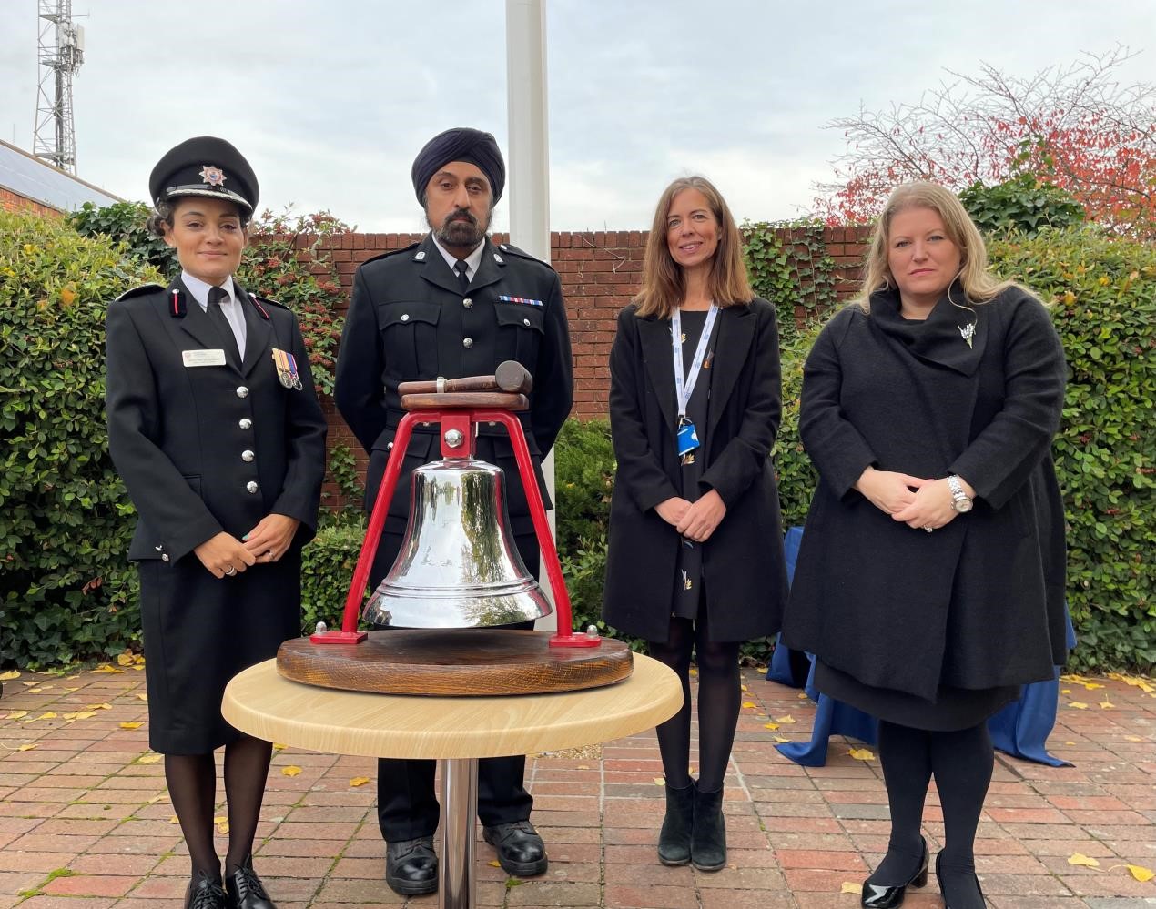 PCC Donna Jones standing with, deputy chief fire officer Shantha Dickinson, Chief Supt Raj Kohli and Ros Hartley from the NHS behind a bell