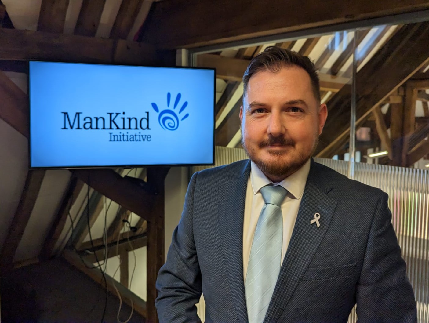 Terry Norton smiling infront of a ManKind Logo