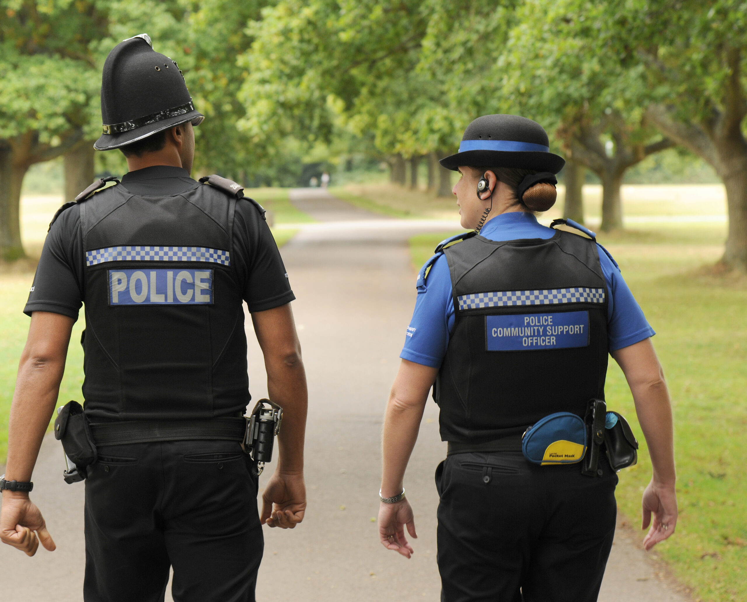 Two officers walking through a green area