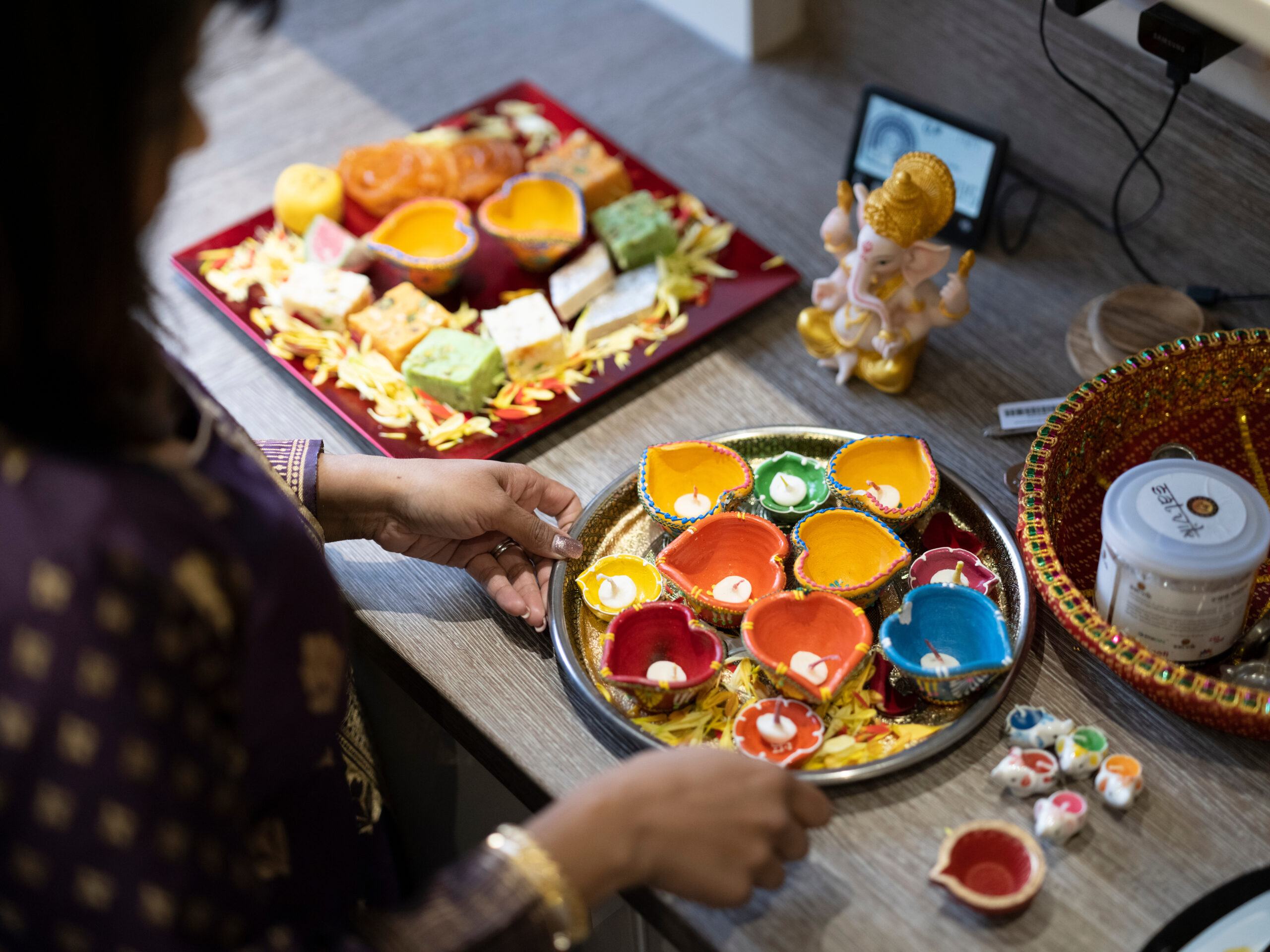 Woman preparing sweet snacks and diyas for Diwali celebration