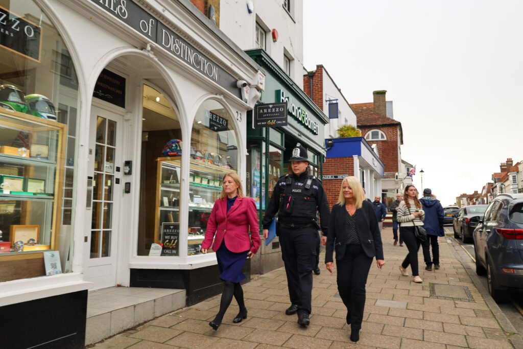 PCC Donna Jones walking along a High St with a uniformed police officer and a lady in smart outfit.