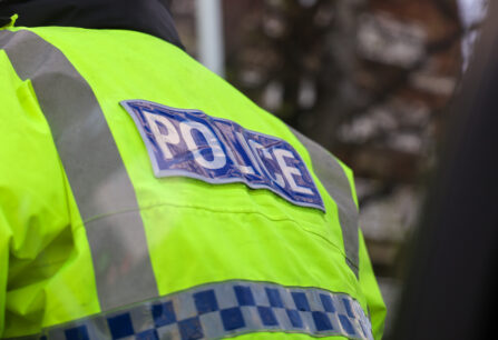 The back of a police officer's hi-vis jacket with the word "Police" showing