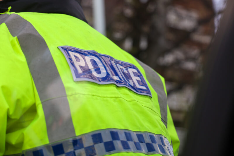 The back of a police officer's hi-vis jacket with the word "Police" showing