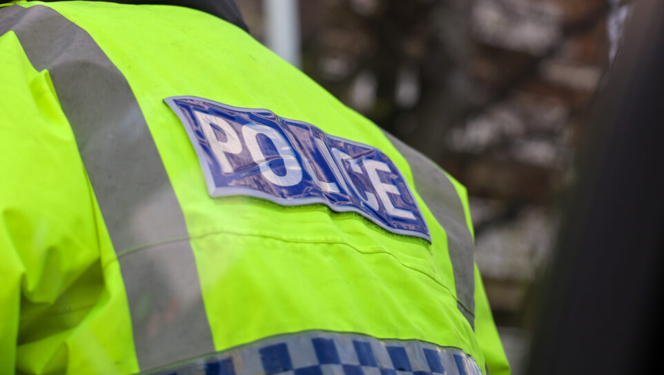 The back of a police officer's hi-vis jacket with the word "Police" showing