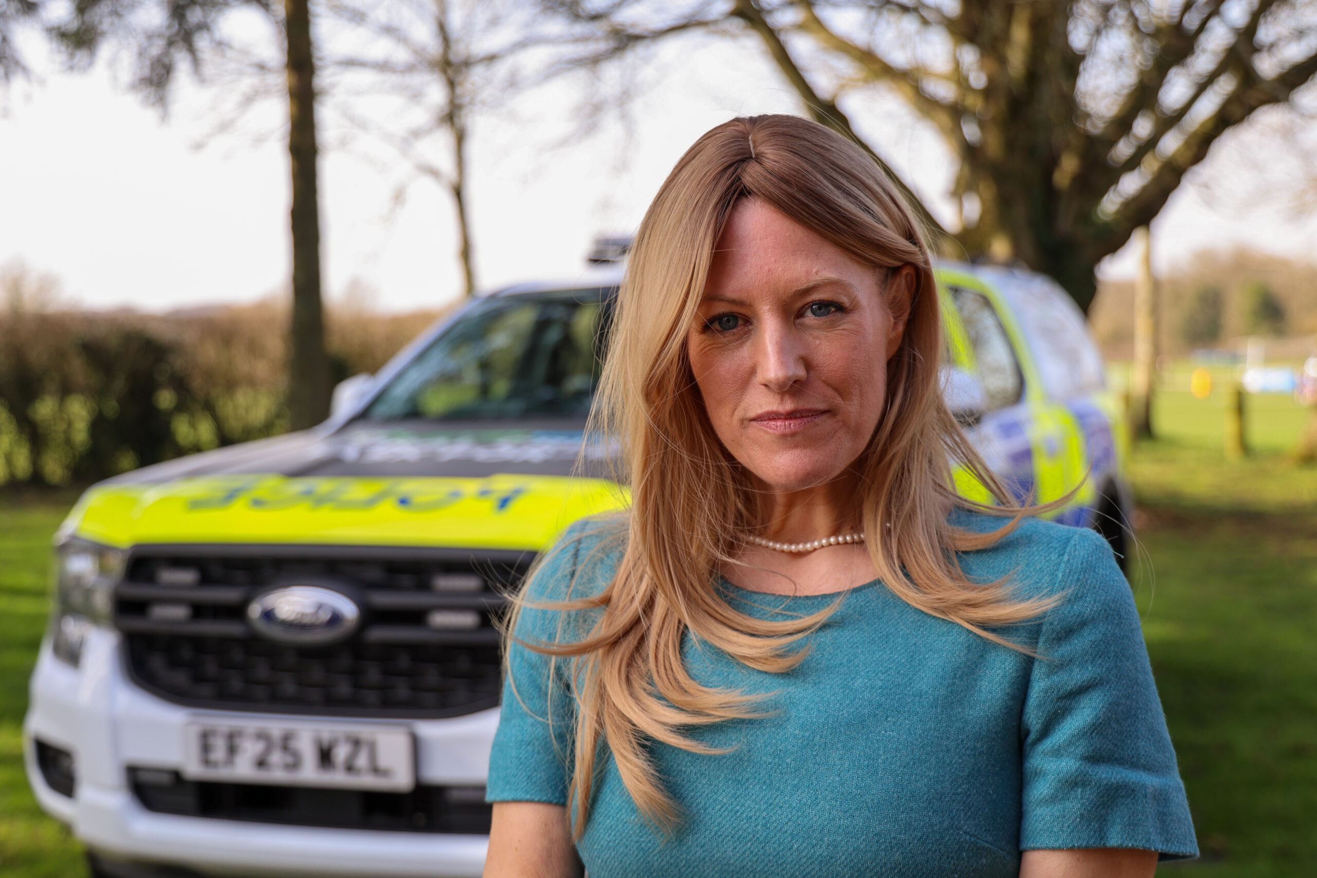PCC Donna Jones looking concerned but pleased standing in front of a large police car in a rural setting