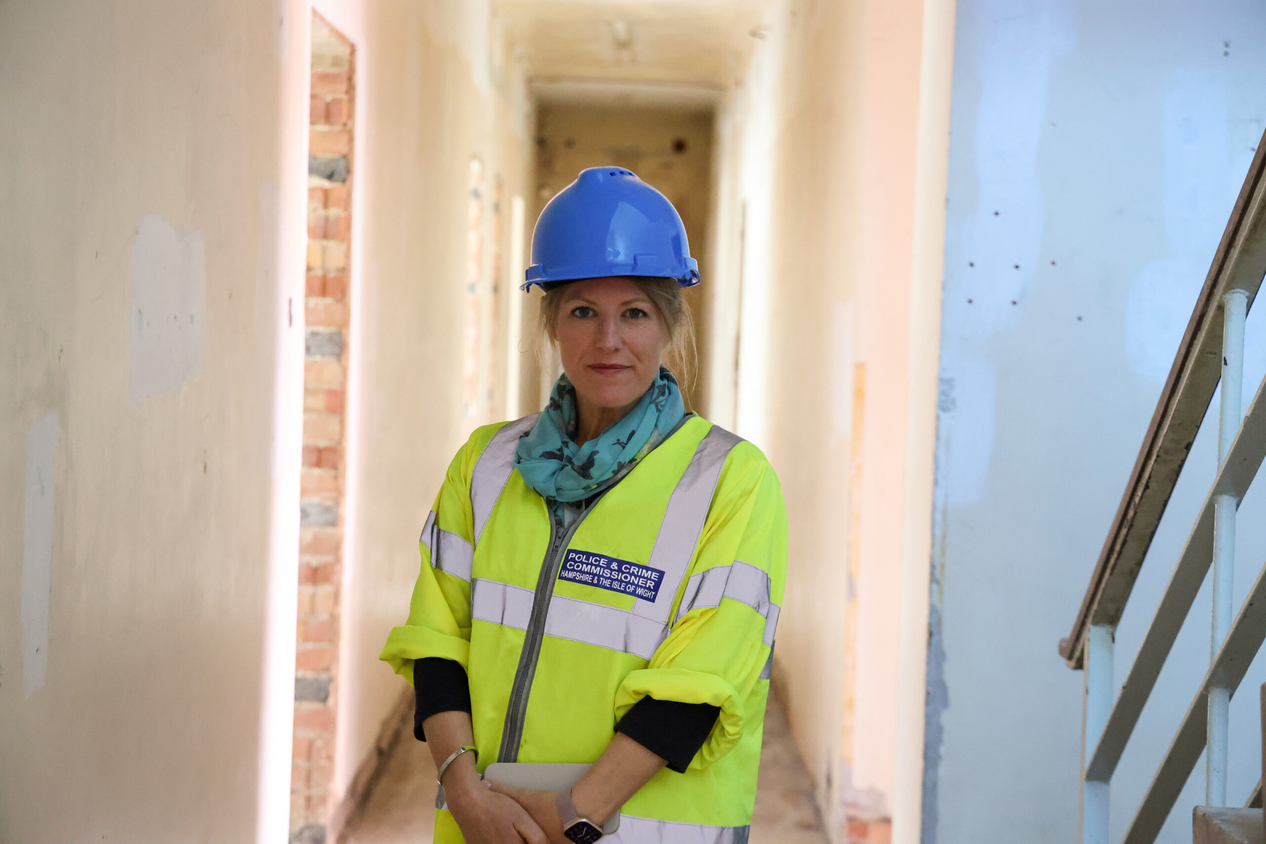 PCC Donna Jones in a yellow high-visibility jacket and a blue hard hat, stood in the corridor of a derelict building.