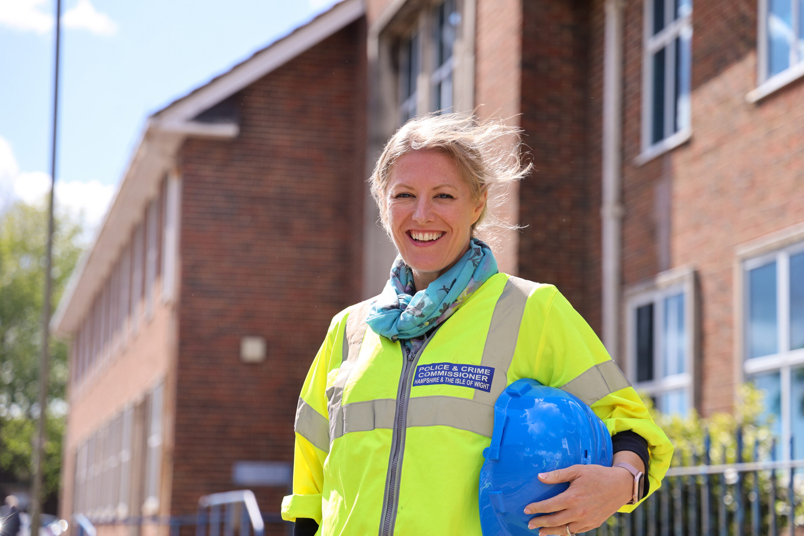 PCC stood smiling outside police station in hi-vis with hard hat