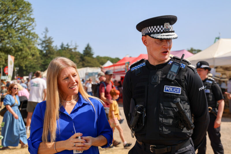 PCC Donna Jones in a blue dress alongside Chief Constable Alexis Boon, in police uniform, at a country fair.