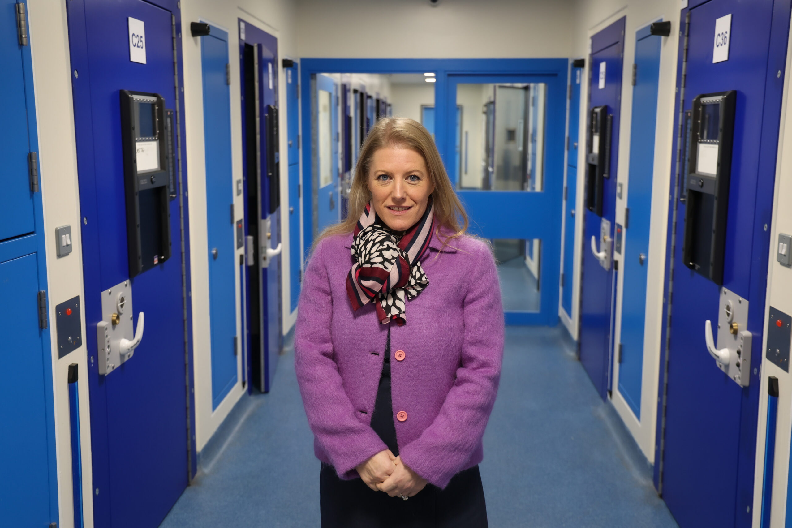 PCC Donna Jones in a purple top, stoood in the corridor of a custody suite.