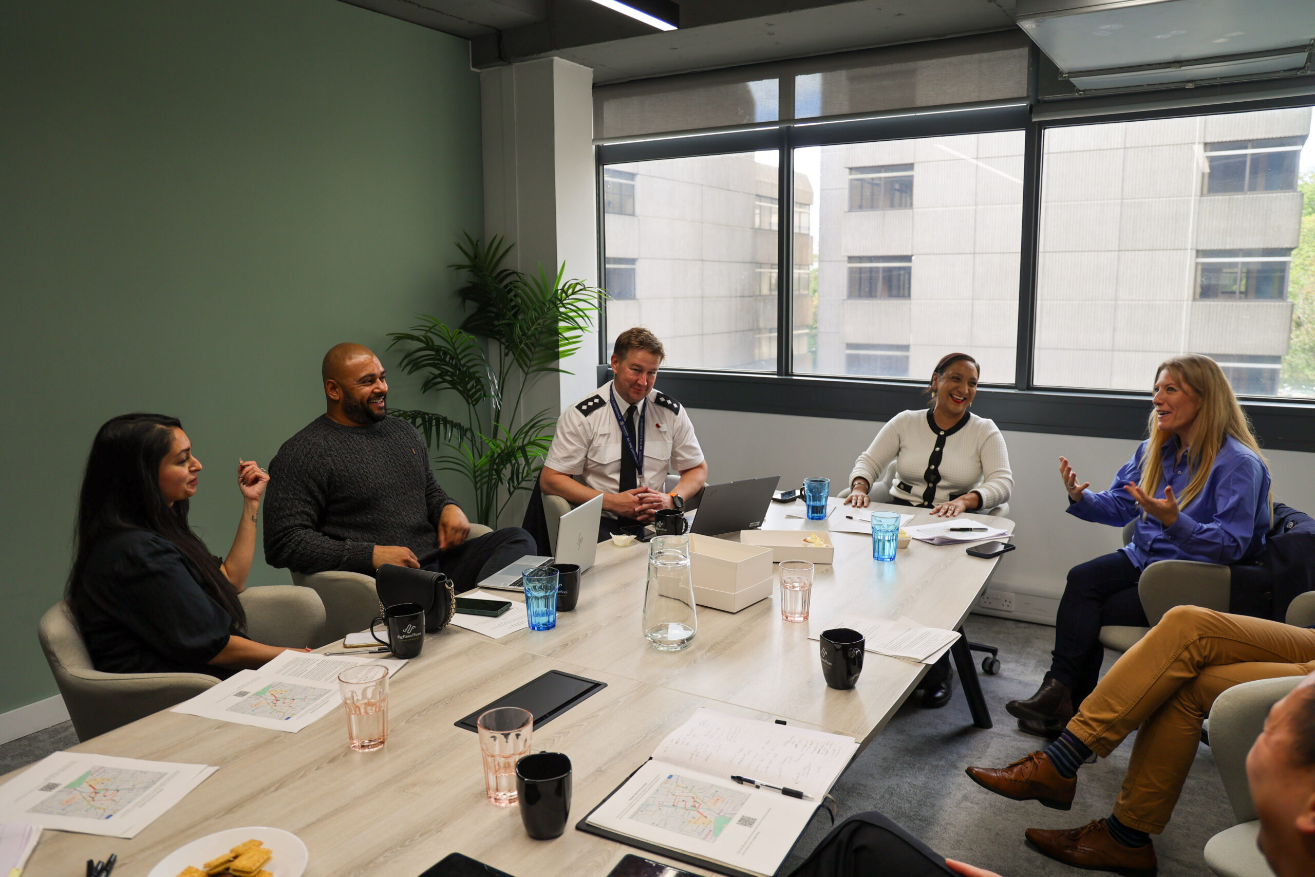 PCC Donna Jones and Satvir Kaur MP meet with local residents and polcie in a meeting room, sat around a large table.